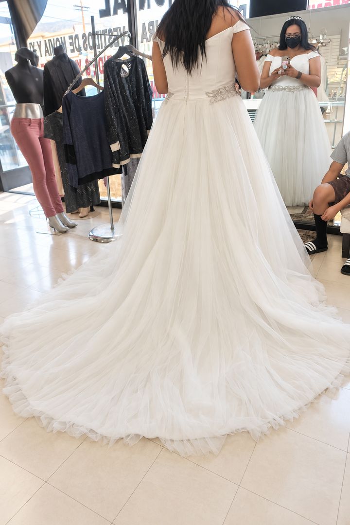 The tulle train of a wedding gown spread on the shop floor